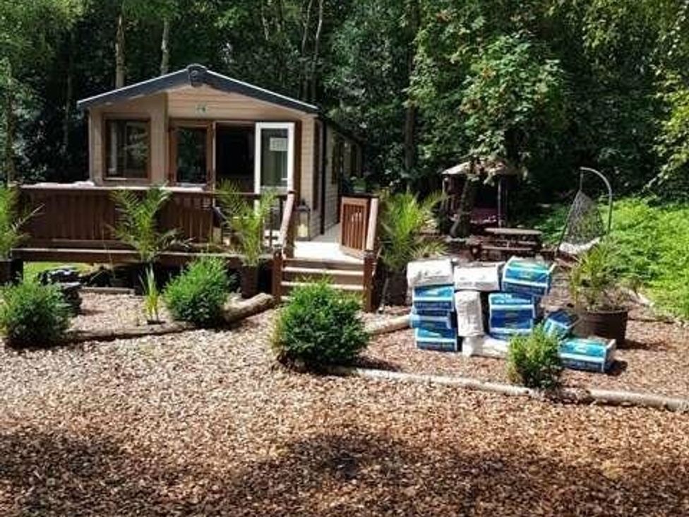a cabin surrounded by trees and landscaping at Wild Duck Holiday Park - Holiday Accommodation 10389 Nr Great Yarmouth