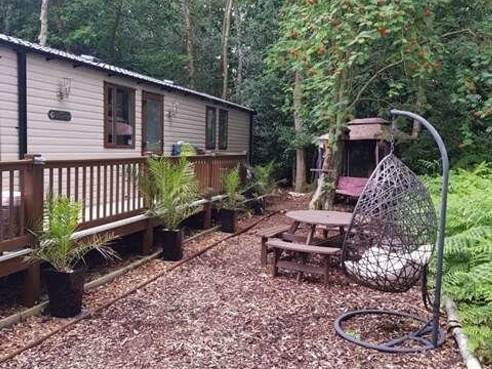 a wooden deck with a hanging chair and picnic table at Wild Duck Holiday Park - Holiday Accommodation 10389 Nr Great Yarmouth