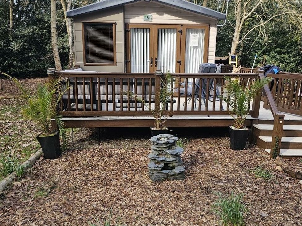a cabin with a deck surrounded by trees at Wild Duck Holiday Park - Holiday Accommodation 10389 Nr Great Yarmouth