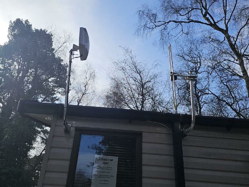 a building roof with two antennas installed and trees in the background at Wild Duck Holiday Park - Holiday Accommodation 10389 Nr Great Yarmouth