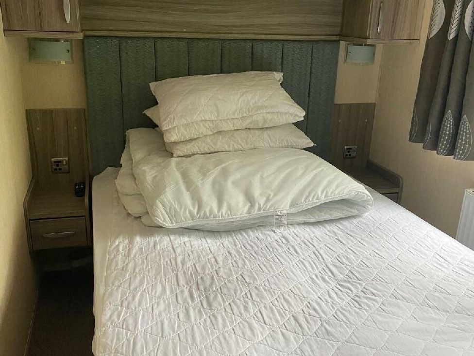 a bed with stacked pillows and a duvet at Wild Duck Holiday Park - Holiday Accommodation 10389 Nr Great Yarmouth