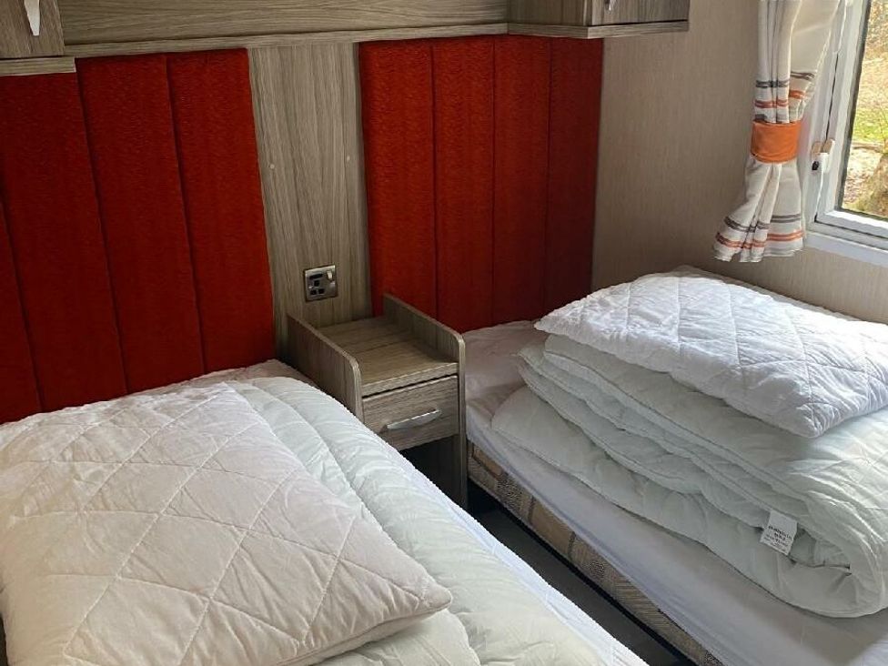 a bedroom with two single beds and stacked bedding at Wild Duck Holiday Park - Holiday Accommodation 10389 Nr Great Yarmouth