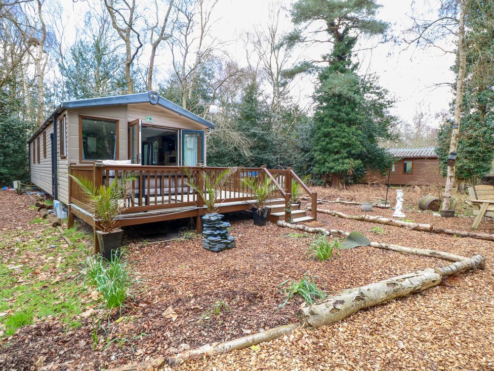 A cabin exterior with a deck and planters at Wild Duck Holiday Park in Belton, Norfolk