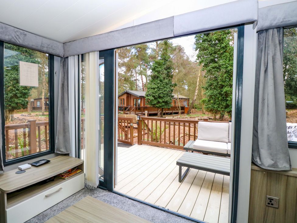 A living room with a view of a deck at Wild Duck Holiday Park in Belton, Norfolk