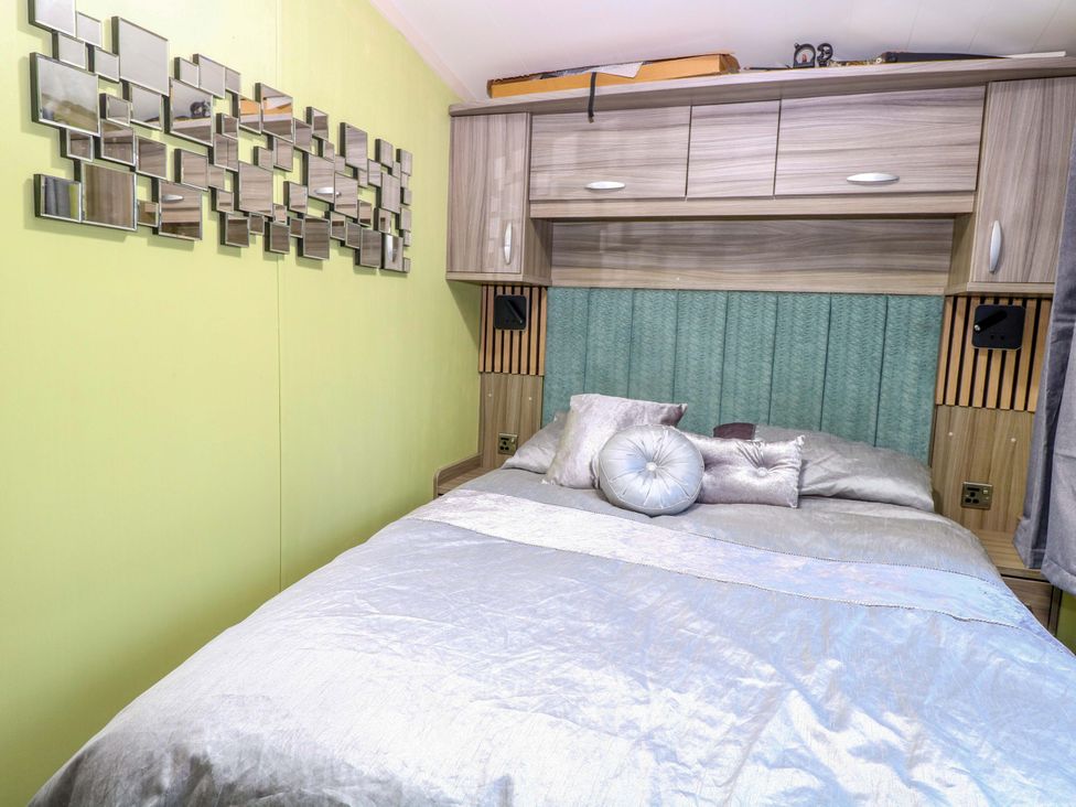 A bedroom with a bed and mirror at Wild Duck Holiday Park, Belton, Norfolk