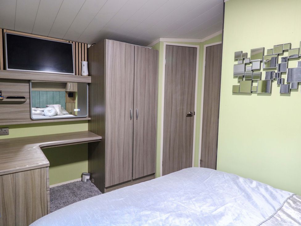 A bedroom with a bed, wardrobe, and television at Wild Duck Holiday Park in Belton, Norfolk