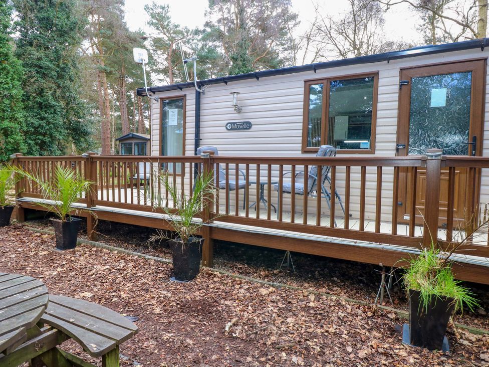 An outdoor cabin with a wooden deck and seating at Wild Duck Holiday Park in Belton, Norfolk
