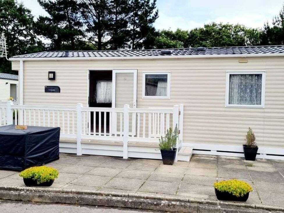 a holiday caravan with a white porch and planters at Shorefield Country Park - Holiday Accommodation 10622 Milford On Sea