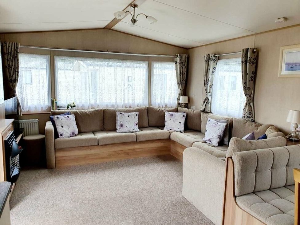 a living room with a large L-shaped couch and curtains at Shorefield Country Park - Holiday Accommodation 10622 Milford On Sea
