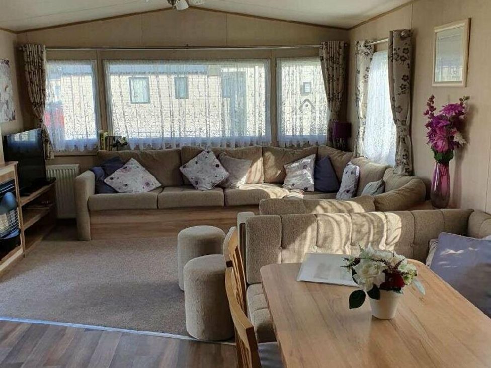 a living room with a large sofa, coffee table, and dining area at Shorefield Country Park - Holiday Accommodation 10622 in Milford On Sea
