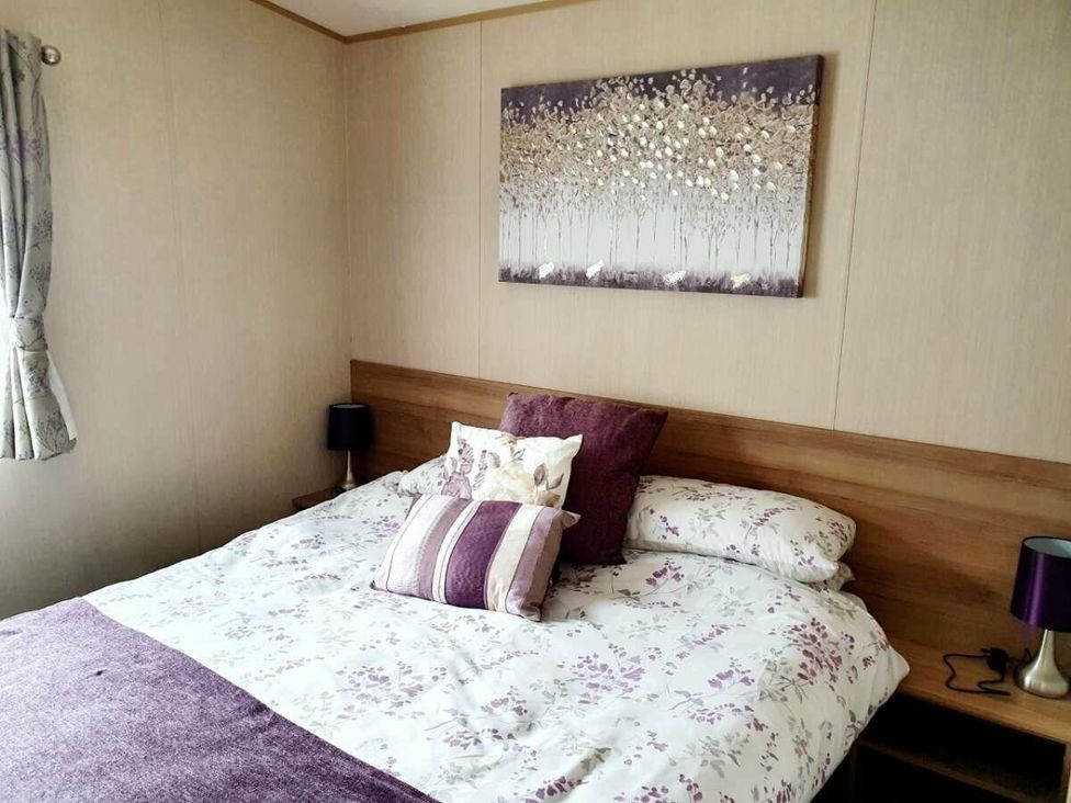 a bedroom with a bed, decorative pillows, and a wall art piece at Shorefield Country Park - Holiday Accommodation 10622 in Milford On Sea