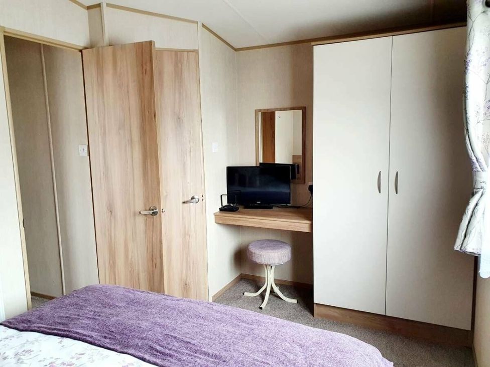a bedroom with a desk, mirror, and wardrobe at Shorefield Country Park - Holiday Accommodation 10622 in Milford On Sea