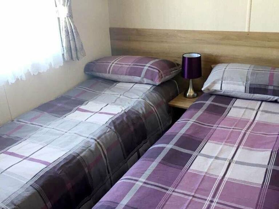 a bedroom with two twin beds and a small bedside lamp at Shorefield Country Park - Holiday Accommodation 10622 in Milford On Sea