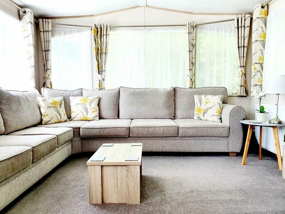 a living room with a gray sectional sofa and floral cushions at Shorefield Country Park - Holiday Accommodation 10821 in Milford On Sea