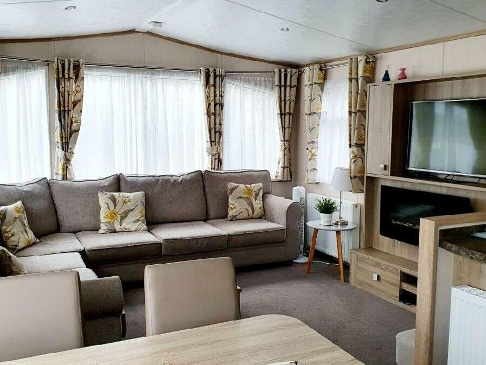 a living room with a sofa, coffee table, TV, and curtains at Shorefield Country Park - Holiday Accommodation 10821 in Milford On Sea