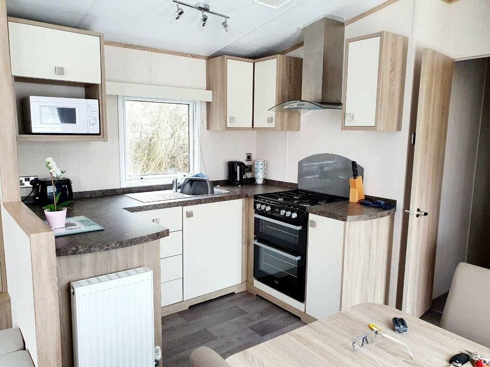 a kitchen area with cabinets, a stove, and a microwave at Shorefield Country Park - Holiday Accommodation 10821 in Milford On Sea