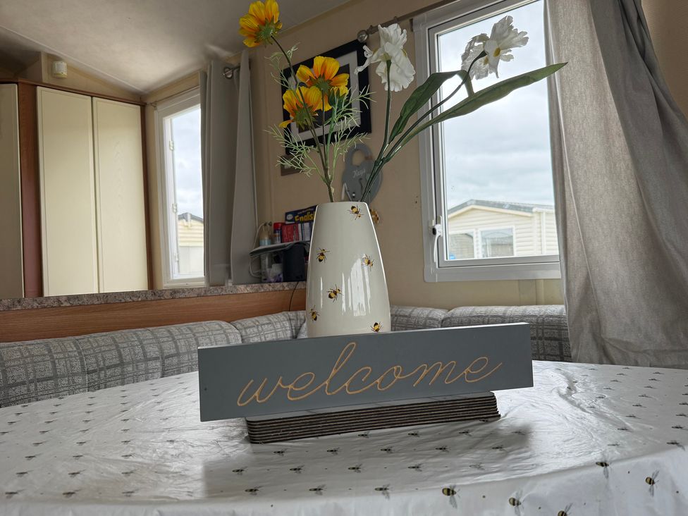 A dining room with a welcome sign and flowers in a vase at Cala Gran Holiday Park - Holiday Accommodation 10830 Fleetwood