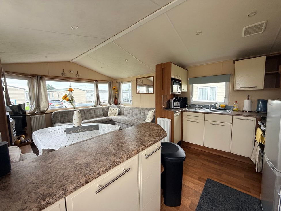 A living room with a kitchen area featuring a couch and kitchen appliances at Cala Gran Holiday Park - Holiday Accommodation 10830, Fleetwood