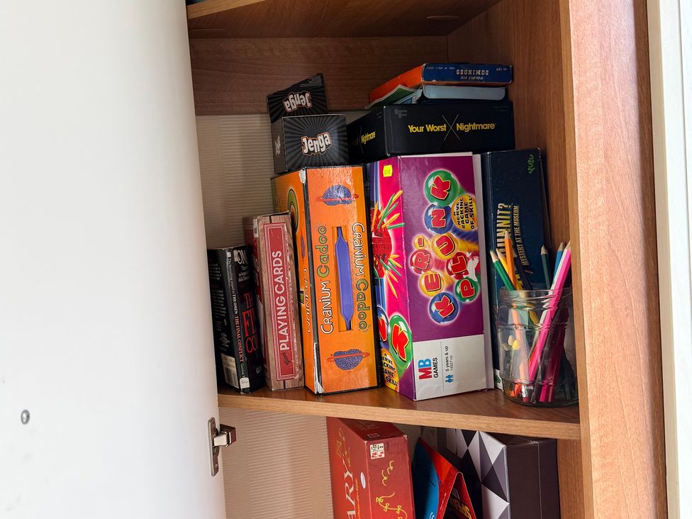 A shelf with board games and colored pencils at Cala Gran Holiday Park - Holiday Accommodation 10830 Fleetwood