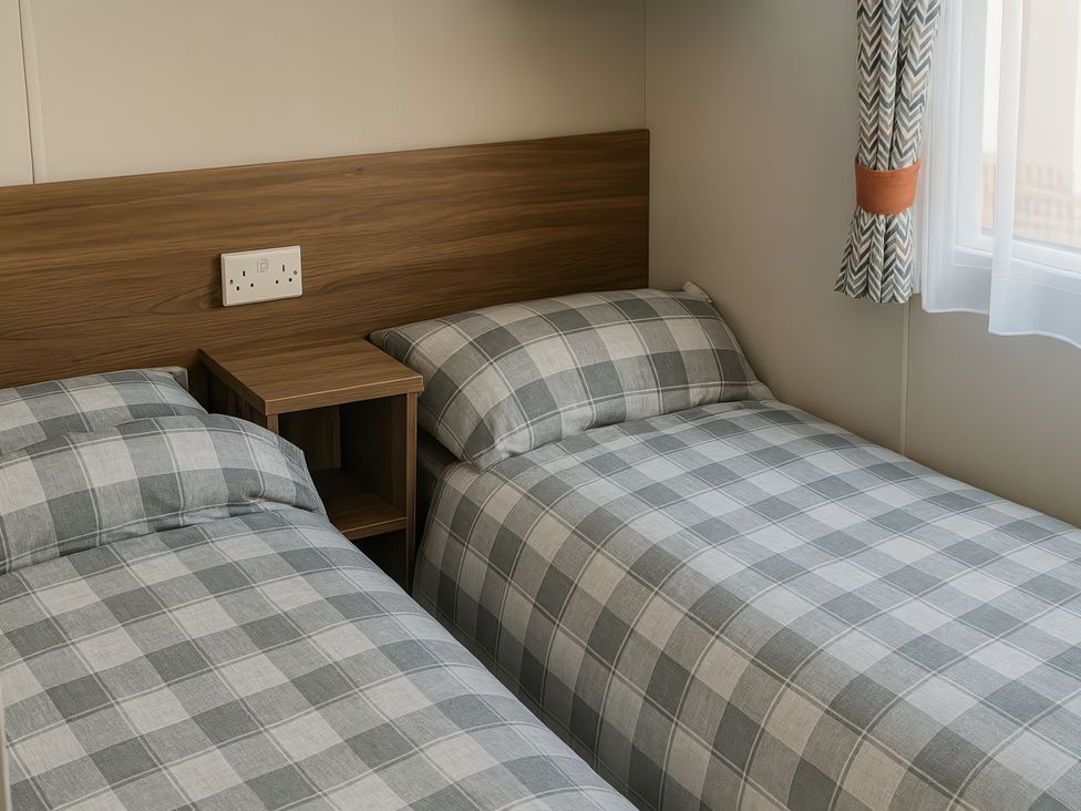 two single beds with plaid bedding in a room at Freshwater Beach Holiday Park - Holiday Accommodation 12281 in Burton Bradstock