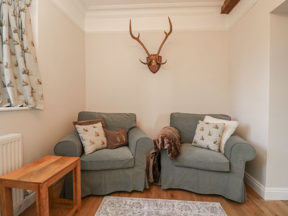 A snug with two armchairs and a wooden side table at Maud Heath's Snug in Chippenham