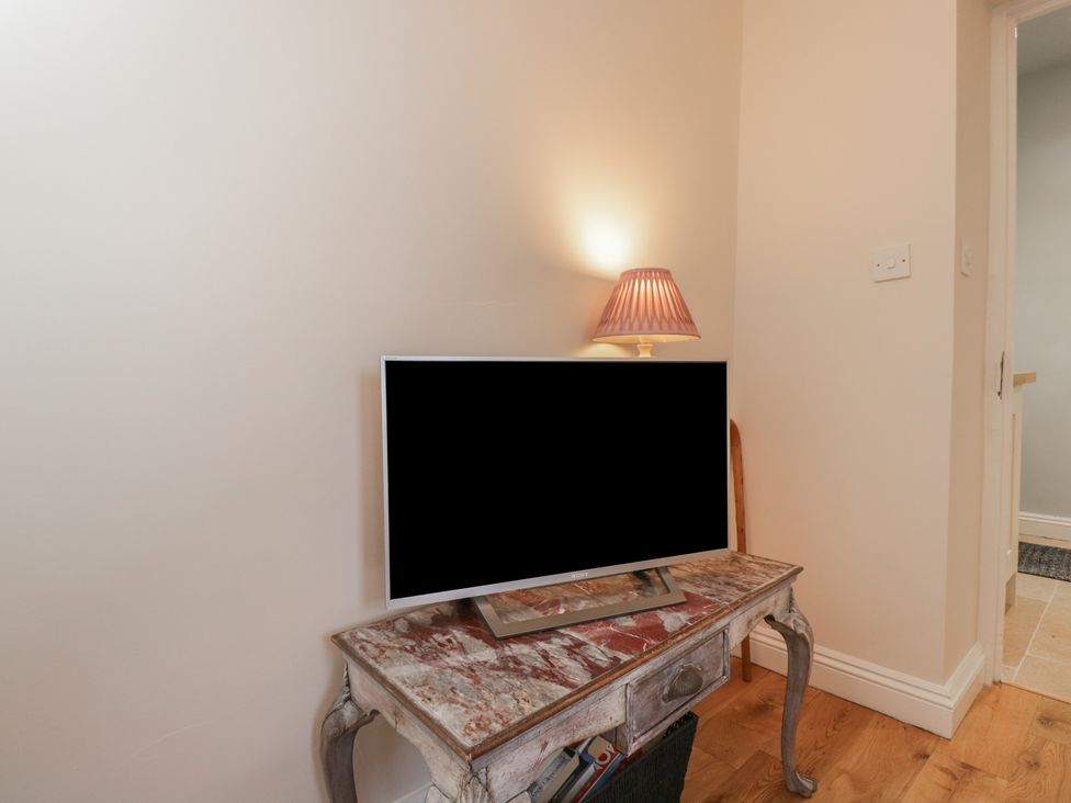 A snug with a television on a table and a lamp at Maud Heath's Snug in Chippenham