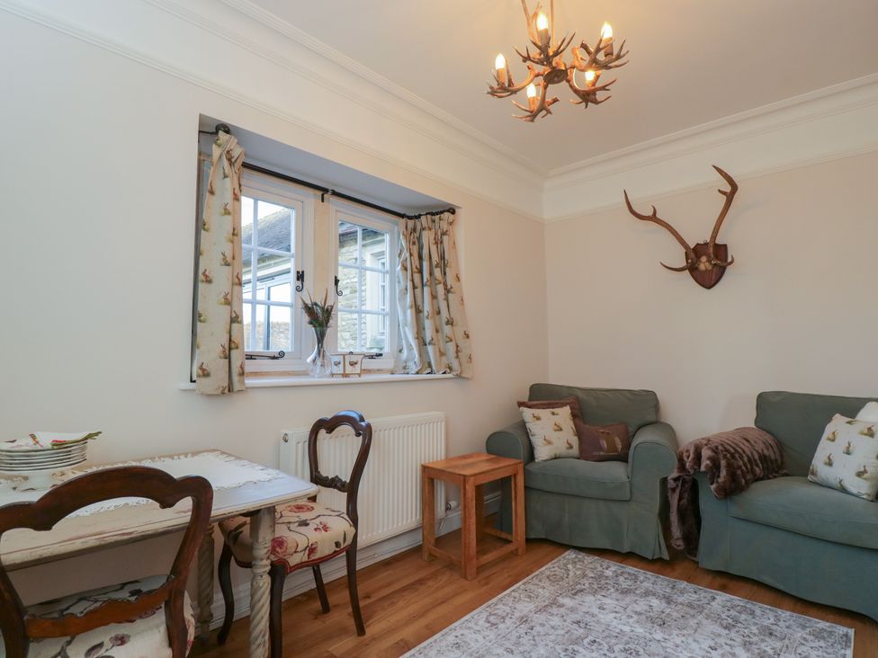 A living room with a sofa, table, and windows at Maud Heath's Snug in Chippenham