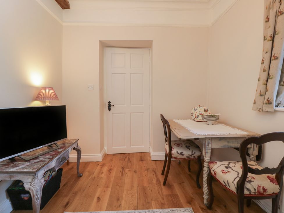 A snug with a television and dining table at Maud Heath's Snug in Chippenham