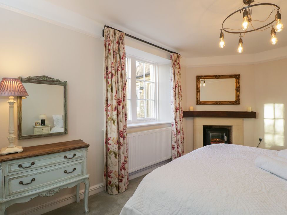 A bedroom with a bed, mirror, lamp and fireplace at Maud Heath's Snug in Chippenham