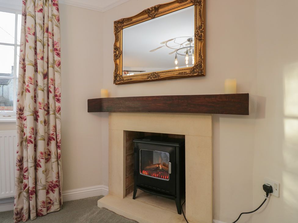 A living room with a fireplace and mirror at Maud Heath's Snug in Chippenham