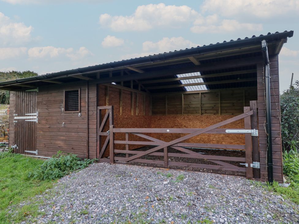 A wooden shed with a gate and gravel area at Maud Heath's Snug Chippenham