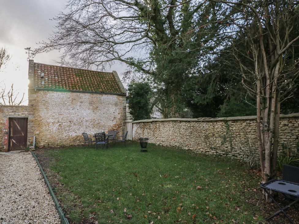 A garden with seating and a stone wall at Maud Heath's Snug in Chippenham