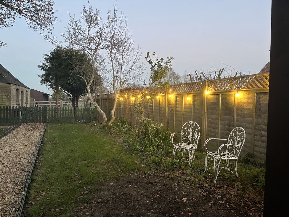 A garden with chairs and lights at Maud Heath's Snug in Chippenham
