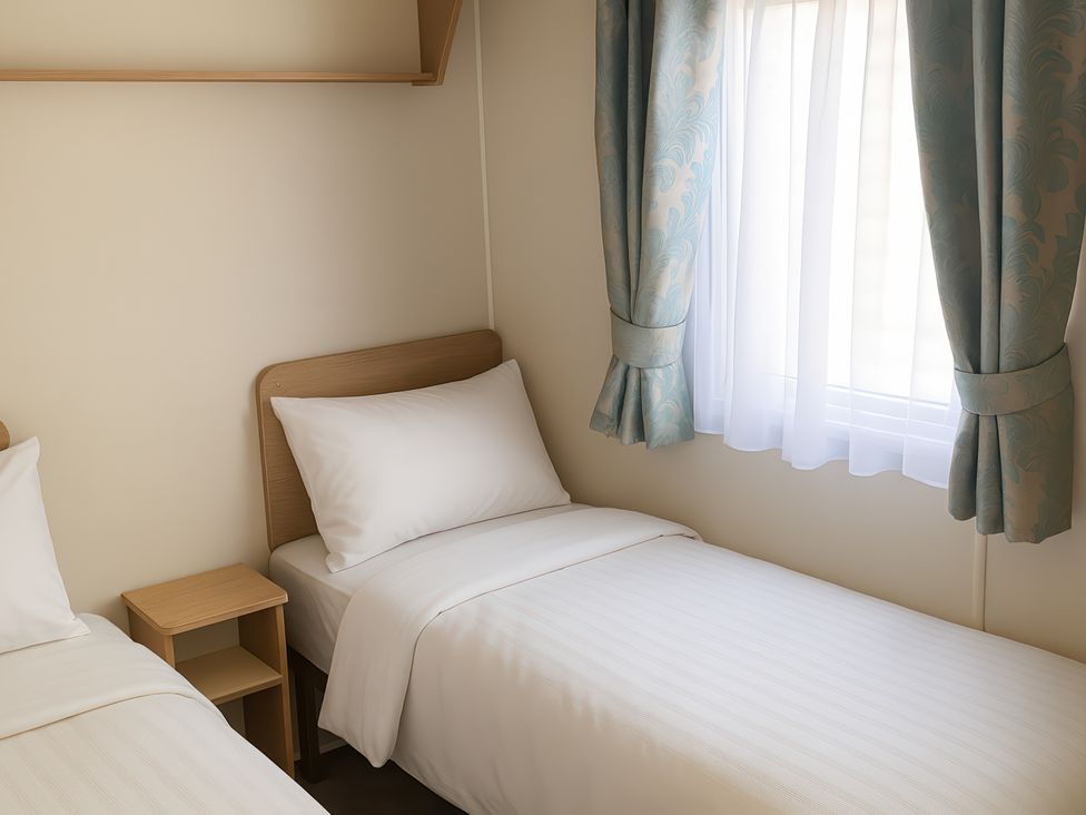 A bedroom with two single beds and a window at Lyons Sunnysands Holiday Park - Holiday Accommodation 12581 Barmouth