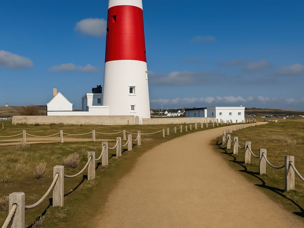 A pathway leading to a lighthouse with a white building nearby at Littlesea Holiday Park - Holiday Accommodation 13127 in Weymouth