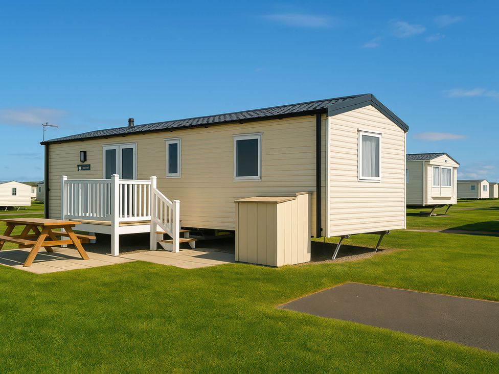 A mobile home with a deck and table at Littlesea Holiday Park - Holiday Accommodation 13127 Weymouth