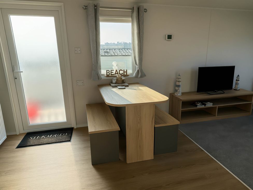 A dining area with a table and bench near a window at Littlesea Holiday Park - Holiday Accommodation 13127 in Weymouth