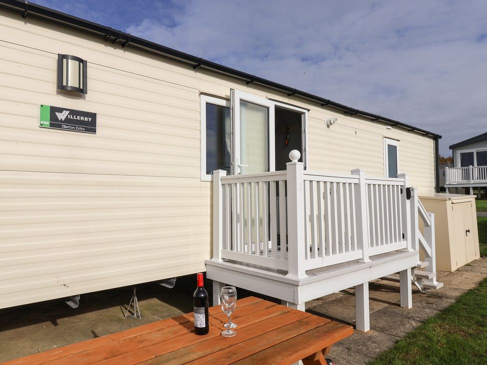 A caravan exterior with a deck and table at Littlesea Holiday Park - Holiday Accommodation 13127 Weymouth
