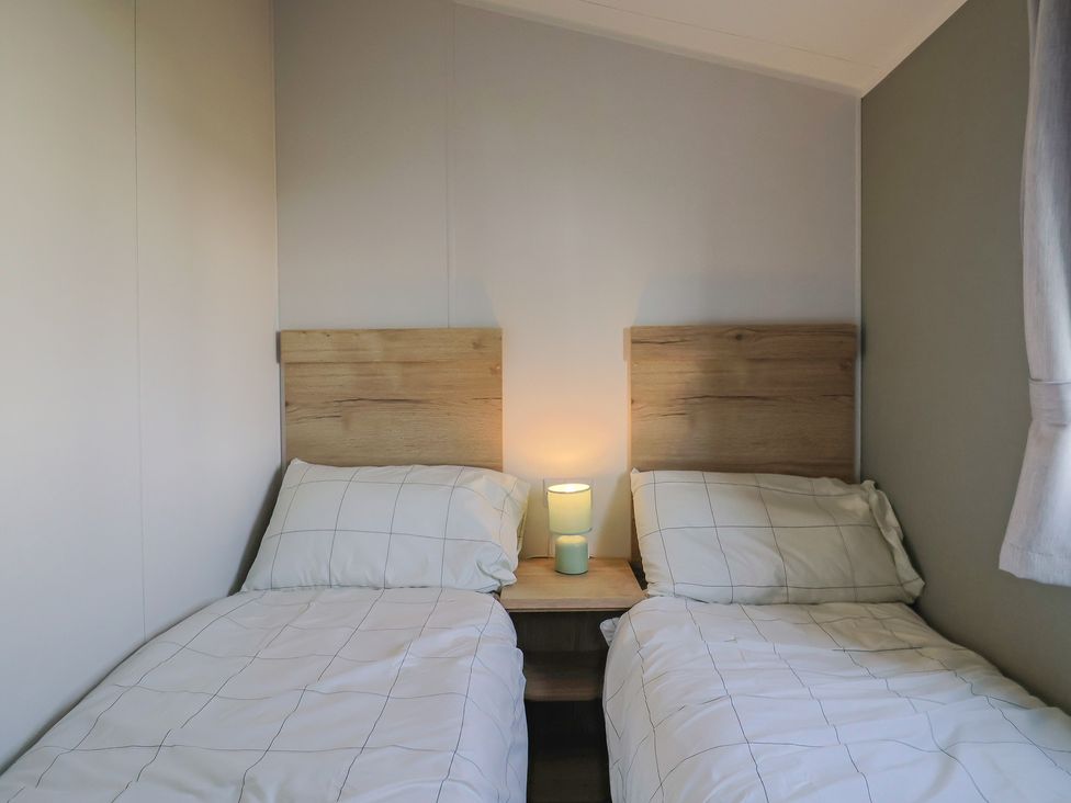 A bedroom with two single beds and a lamp at Littlesea Holiday Park - Holiday Accommodation 13127, Weymouth