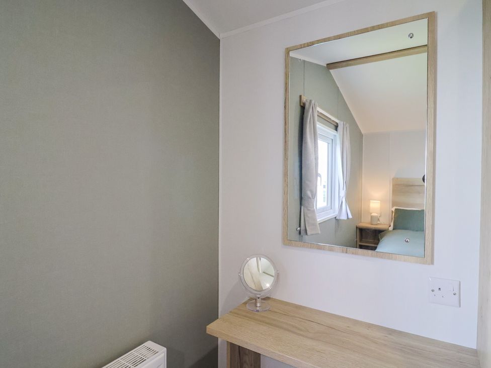 A bedroom with a mirror and a lamp at Littlesea Holiday Park - Holiday Accommodation 13127, Weymouth