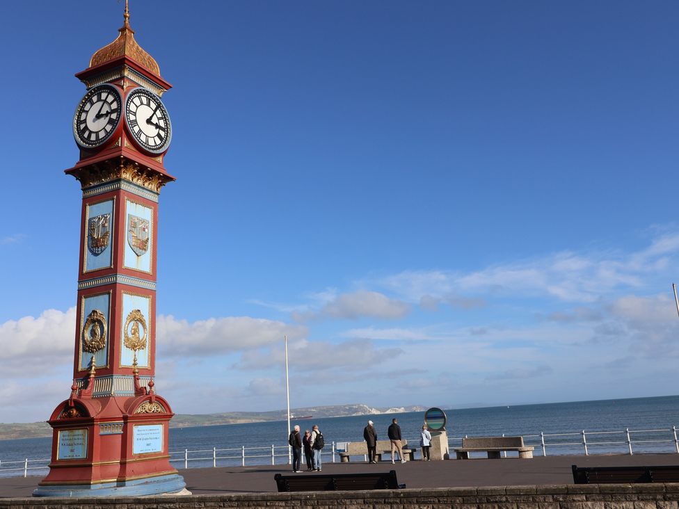 A clock tower near the ocean with people on a promenade at Littlesea Holiday Park - Holiday Accommodation 13127 Weymouth
