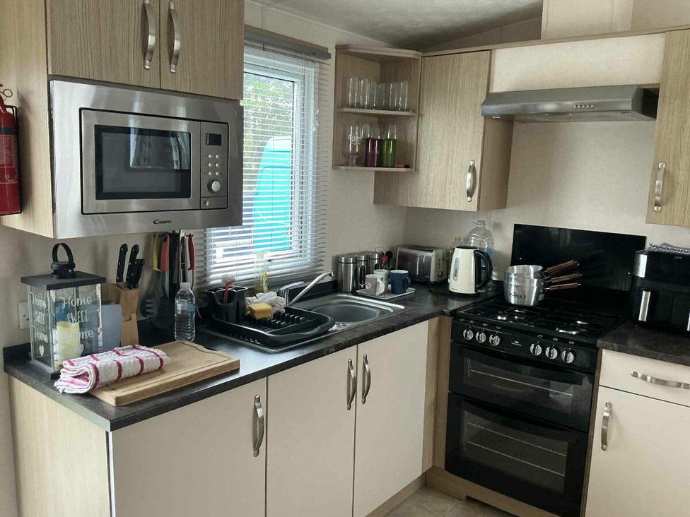 a kitchen with cabinets, a sink, a microwave, and appliances at Golden Palm Resort - Holiday Accommodation 13363 in Skegness