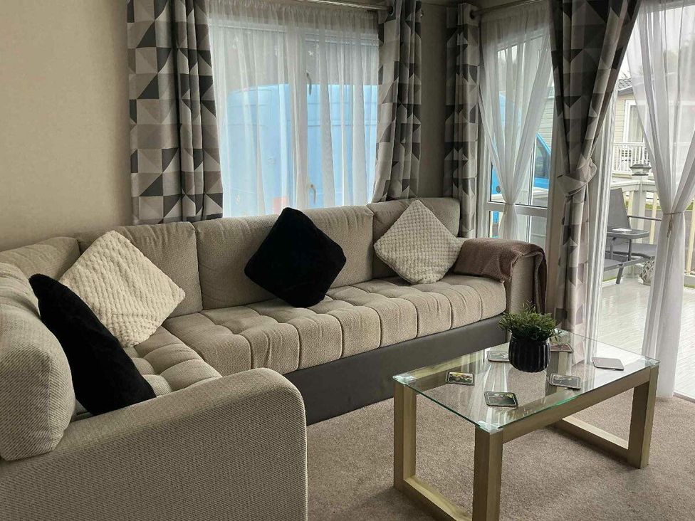 a living room with a sectional sofa and a glass coffee table at Golden Palm Resort - Holiday Accommodation 13363 in Skegness