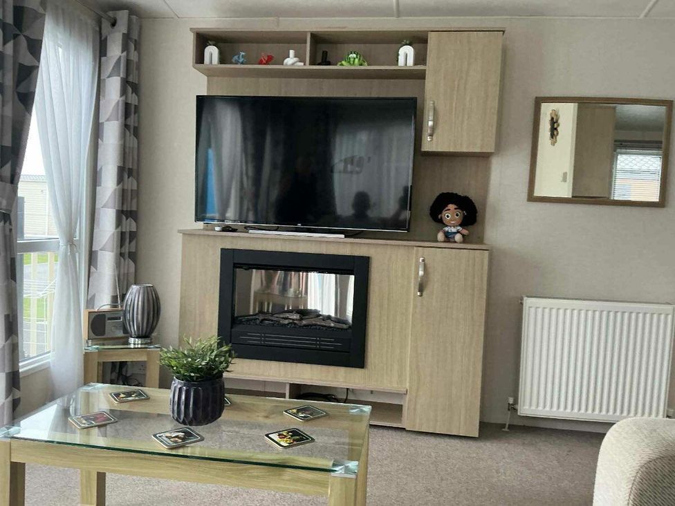 a living room with a television unit and a glass coffee table at Golden Palm Resort - Holiday Accommodation 13363, Skegness