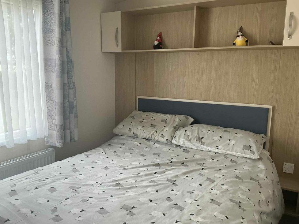 a bedroom with a bed and shelf holding figurines at Golden Palm Resort - Holiday Accommodation 13363 in Skegness