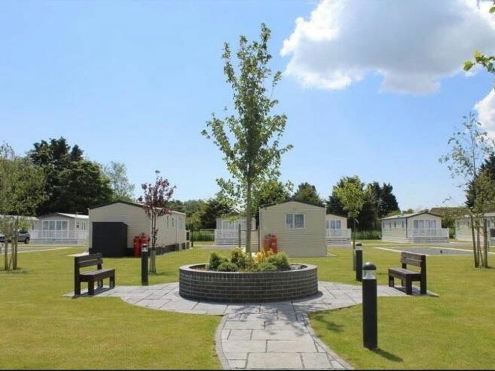 a landscaped area with a central garden feature surrounded by holiday cabins at Golden Palm Resort - Holiday Accommodation 13363 Skegness