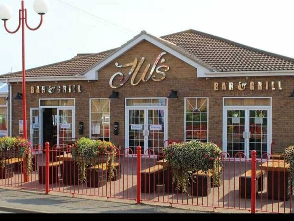a restaurant exterior with signage and planters at Jll's Bar & Grill in Skegness