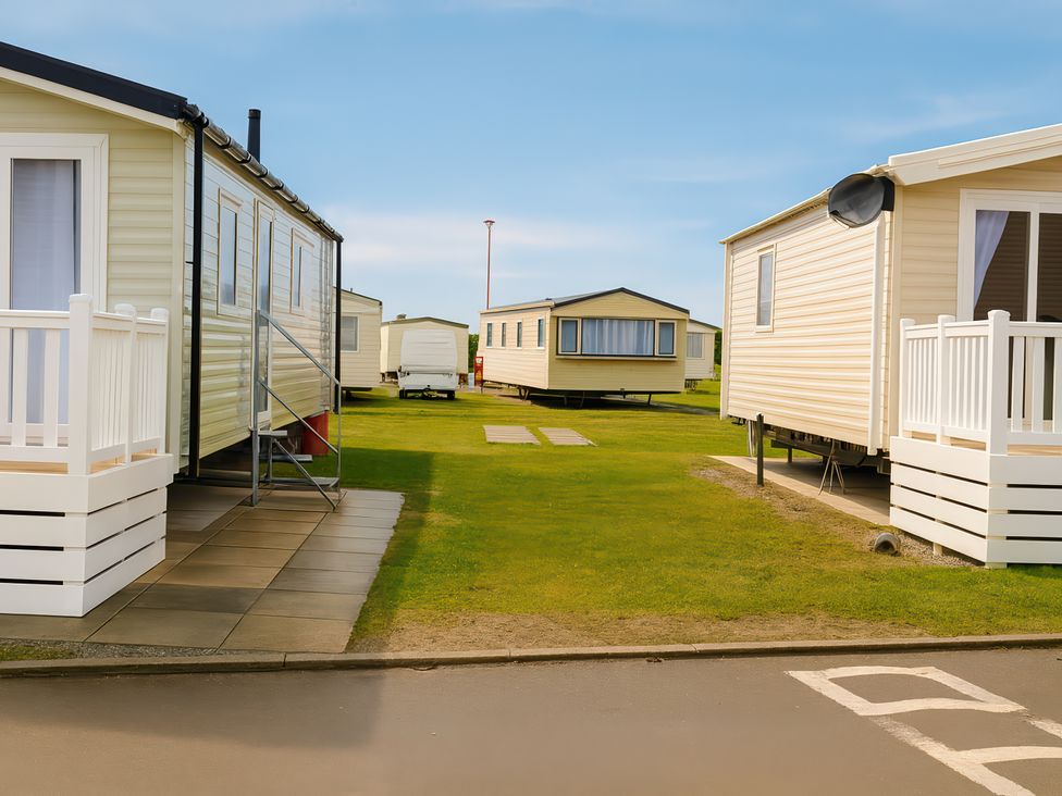 An outdoor area with mobile homes and green grass at Lyons Sunnysands Holiday Park - Holiday Accommodation 13733, Barmouth