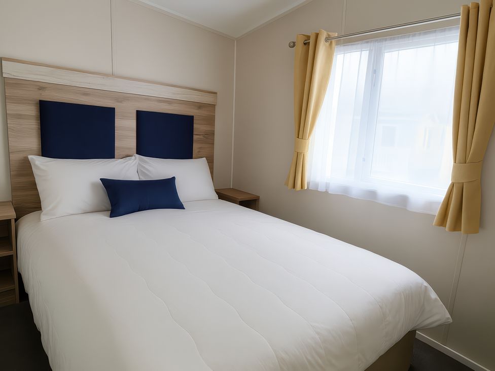 A bedroom with a bed and nightstand at Lyons Sunnysands Holiday Park - Holiday Accommodation 13733, Barmouth