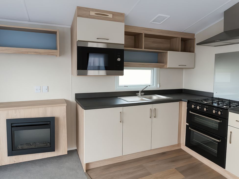 A kitchen with appliances and storage at Lyons Sunnysands Holiday Park - Holiday Accommodation 13733, Barmouth